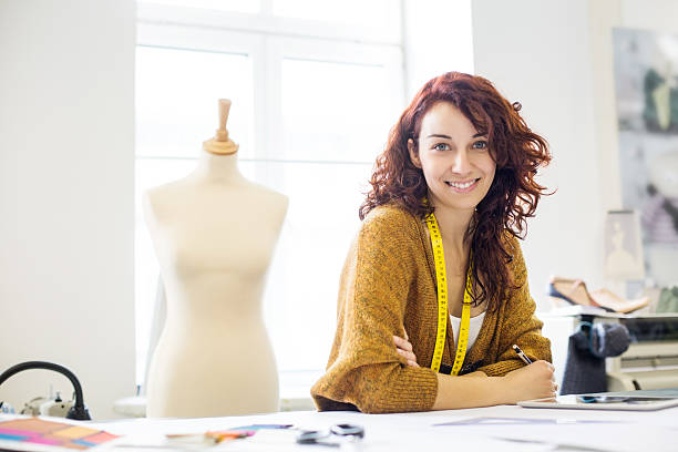 beautiful young female designer sitting at a table in clothing design studio